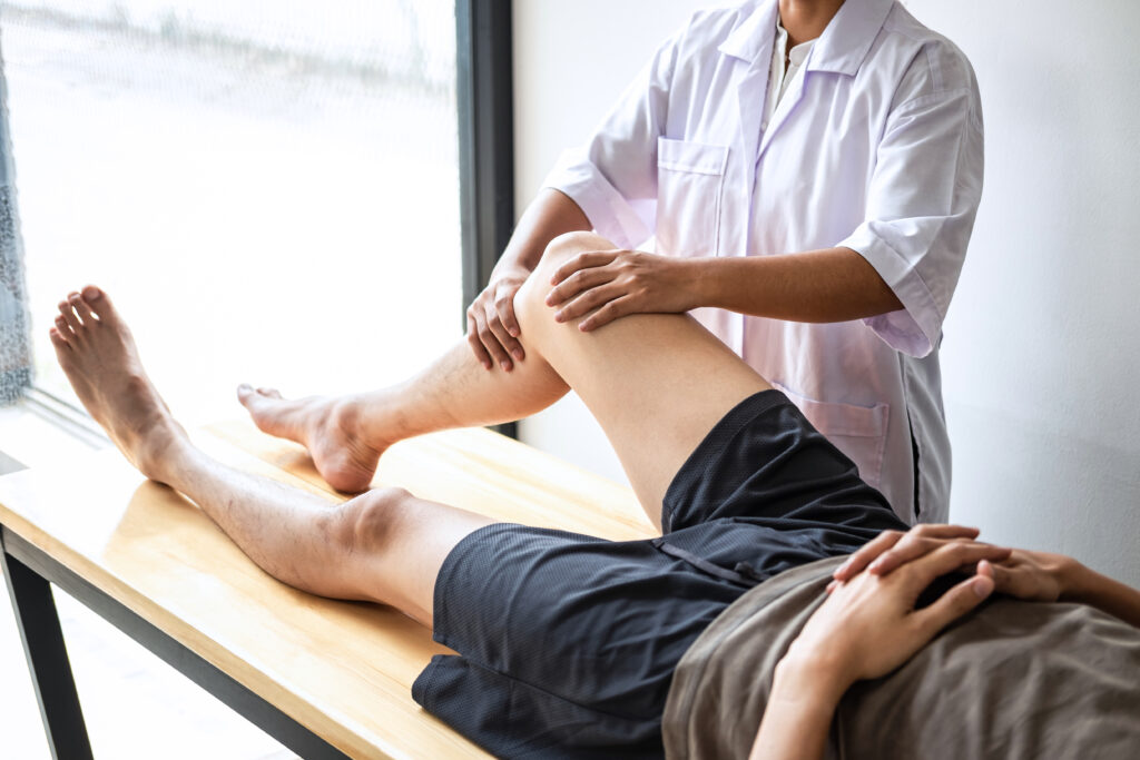 Female,Physiotherapist,Working,Examining,Treating,Injured,Leg,Of,Male,Patient,